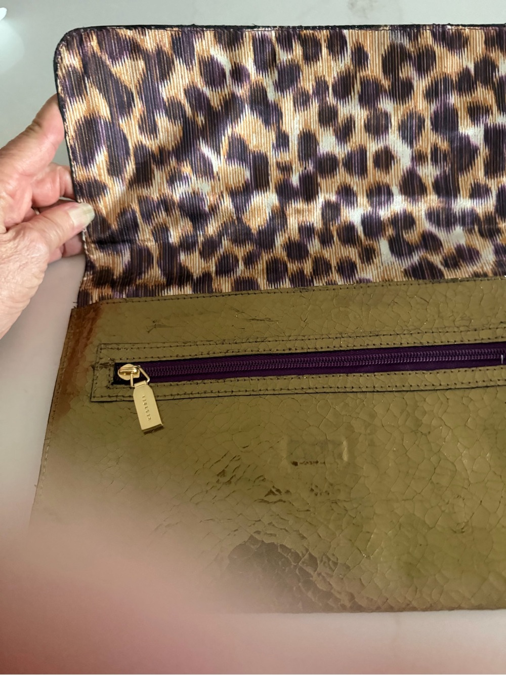 Kestrel Gold Casual Clutch with contrasting purple animal print interior.
